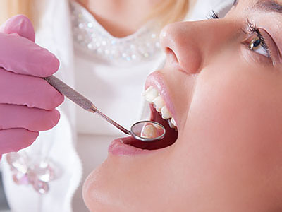 The image shows a dental professional performing an oral procedure on a patient s mouth using dental instruments.