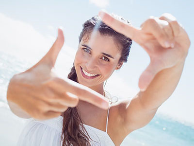 A woman taking a selfie with her fingers held up against the sun.